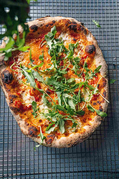 Pizza covered in arugula cheese and tomato