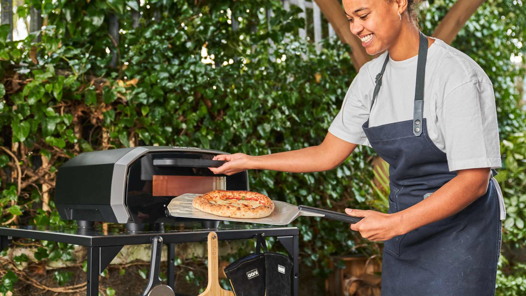 Family cooking pizza around an Ooni pizza oven