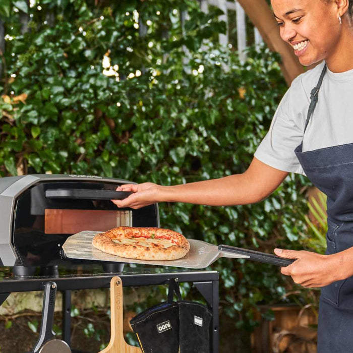Family cooking pizza around an Ooni pizza oven