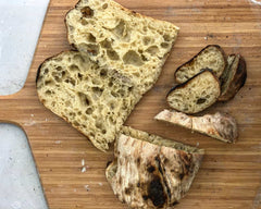 Ciabatta on a wooden pizza peel sliced up and baked using a sourdough ciabatta recipe.