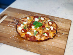 A bar style pizza topped with pepperoni and cheese on a wooden chopping board. Baked with a bar style pizza recipe.