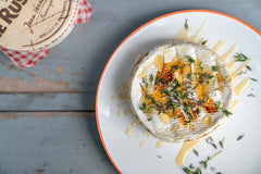 Baked Camembert topped with honey and thyme on a white plate, made using a baked camembert recipe.