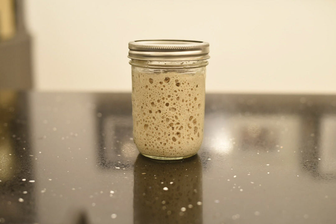 Sourdough starter in a jar on a marble table.