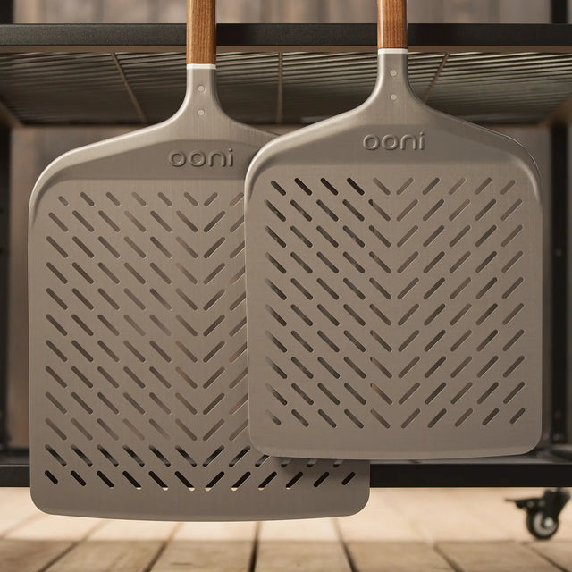 side by side of signature perforated pizza peel hanging from large modular table