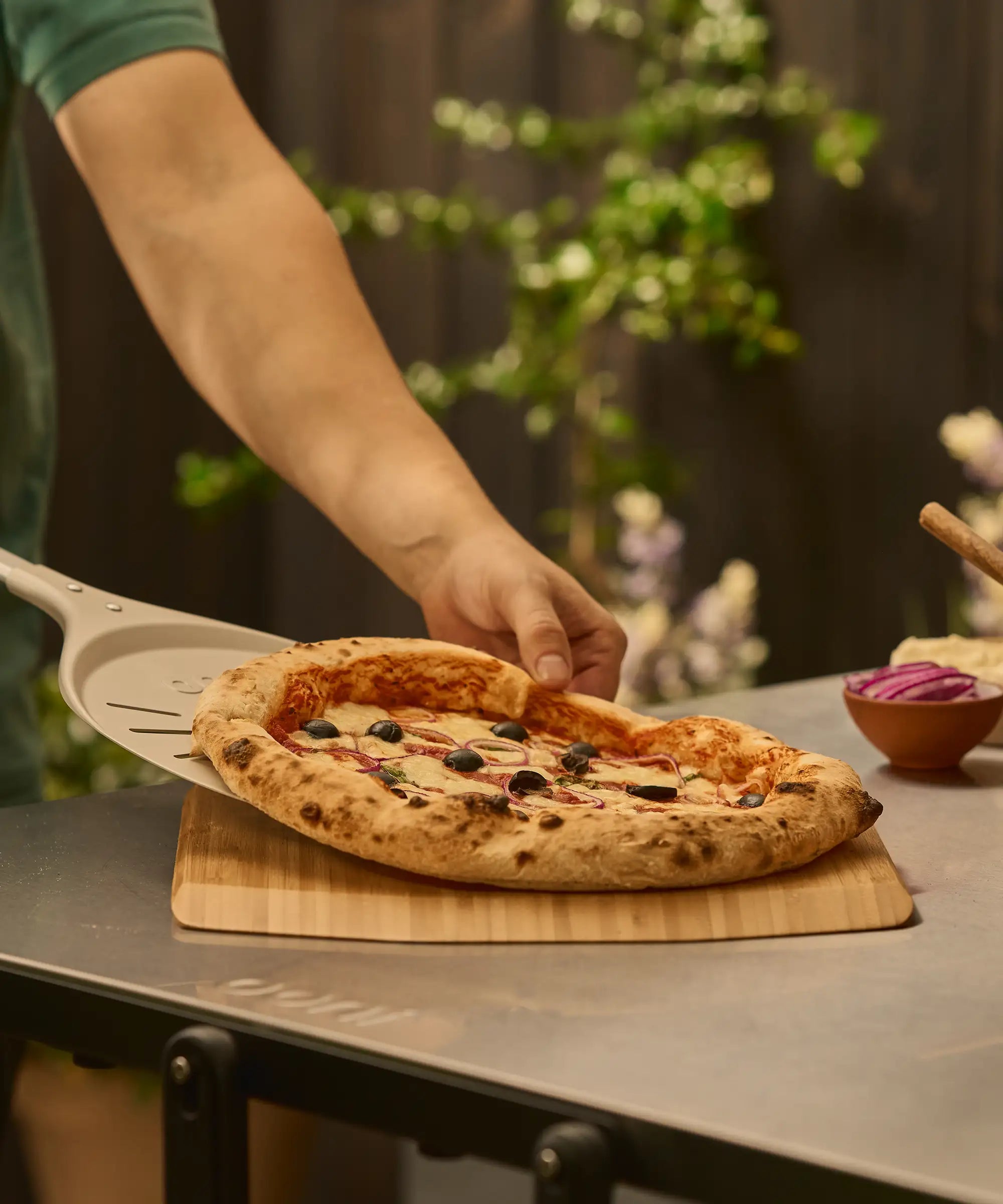 pizza being placed on bamboo pizza peel and serving board with wide turning peel 