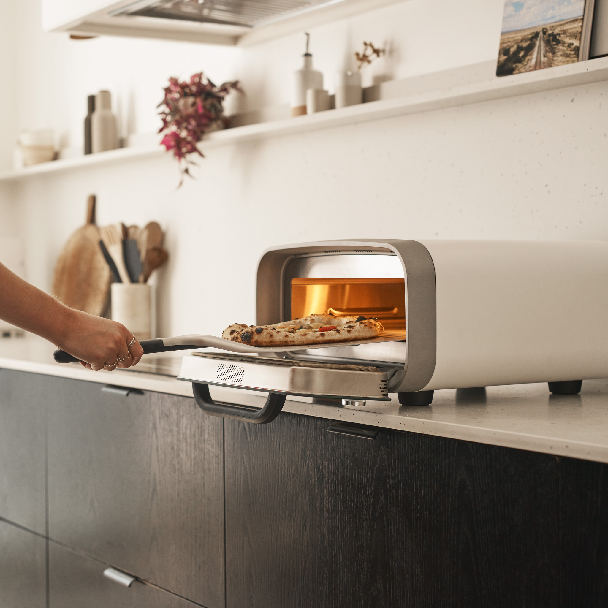 pizza being retrieved from volt 2 electric pizza oven in polar white