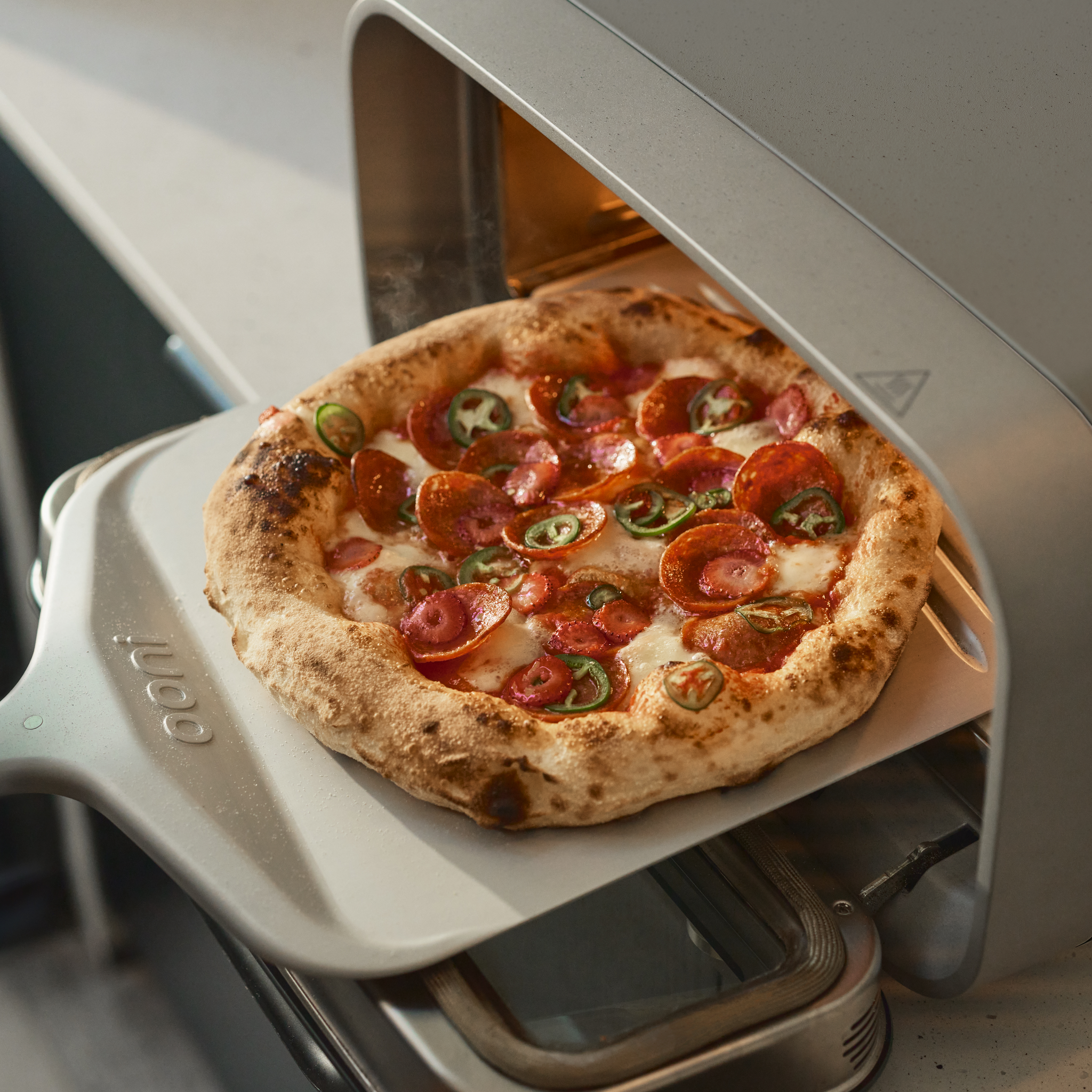 pizza being retrieved from volt 2 electric pizza oven 